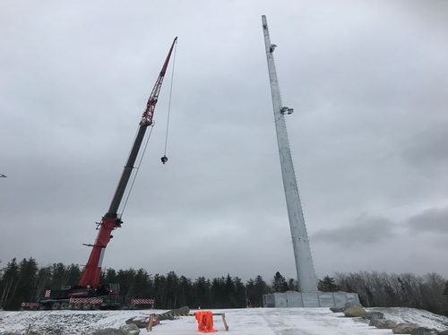 Crane installing telecommunications tower for industrial wireless networks in remote area.